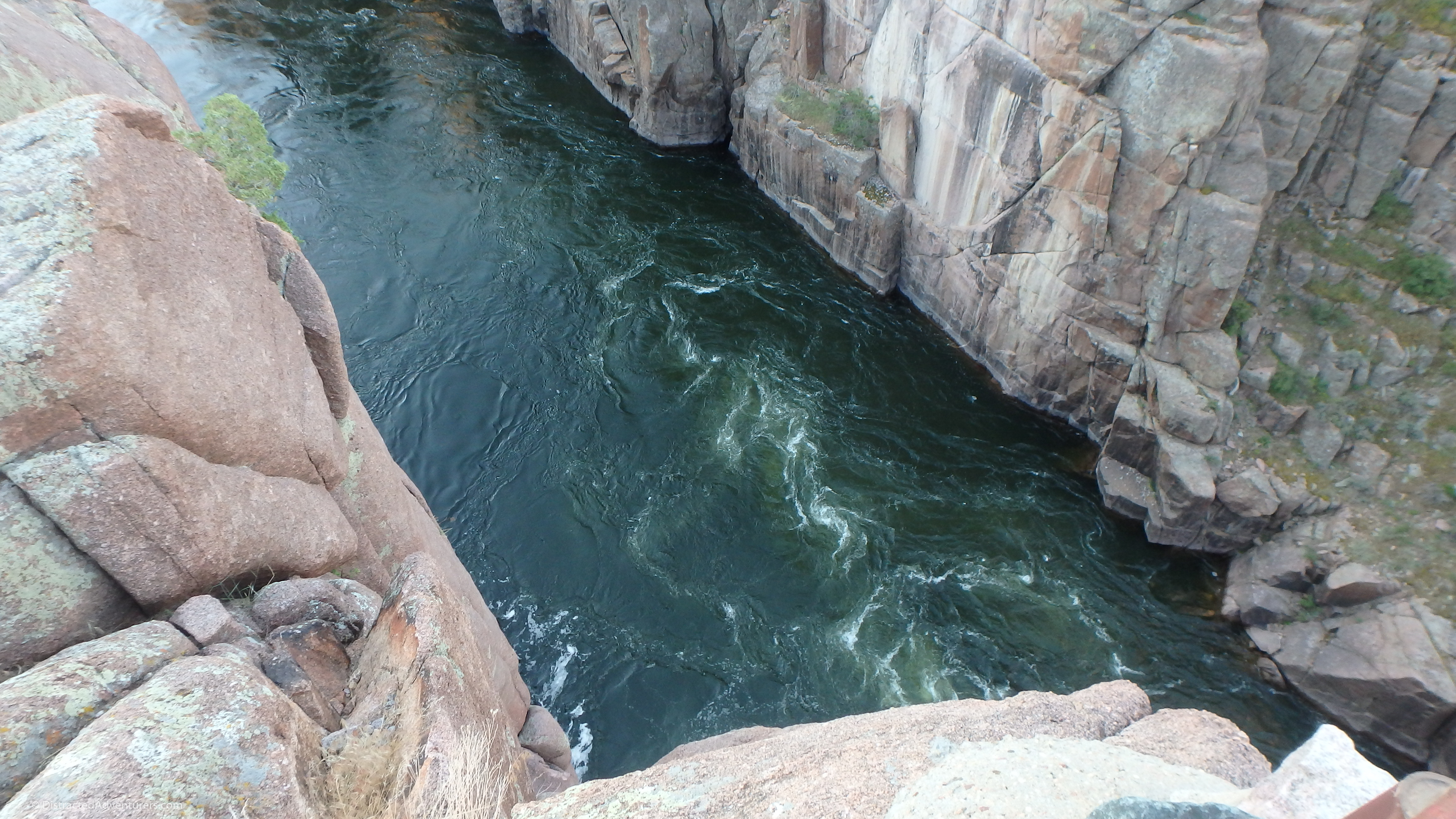 A deep turquoise river flows at the bast of smooth rock walls.